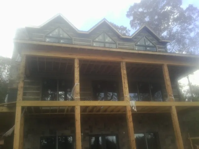 Dormers and porch framing on a large log home under construction — Roof Coating work by our crew in Buckingham