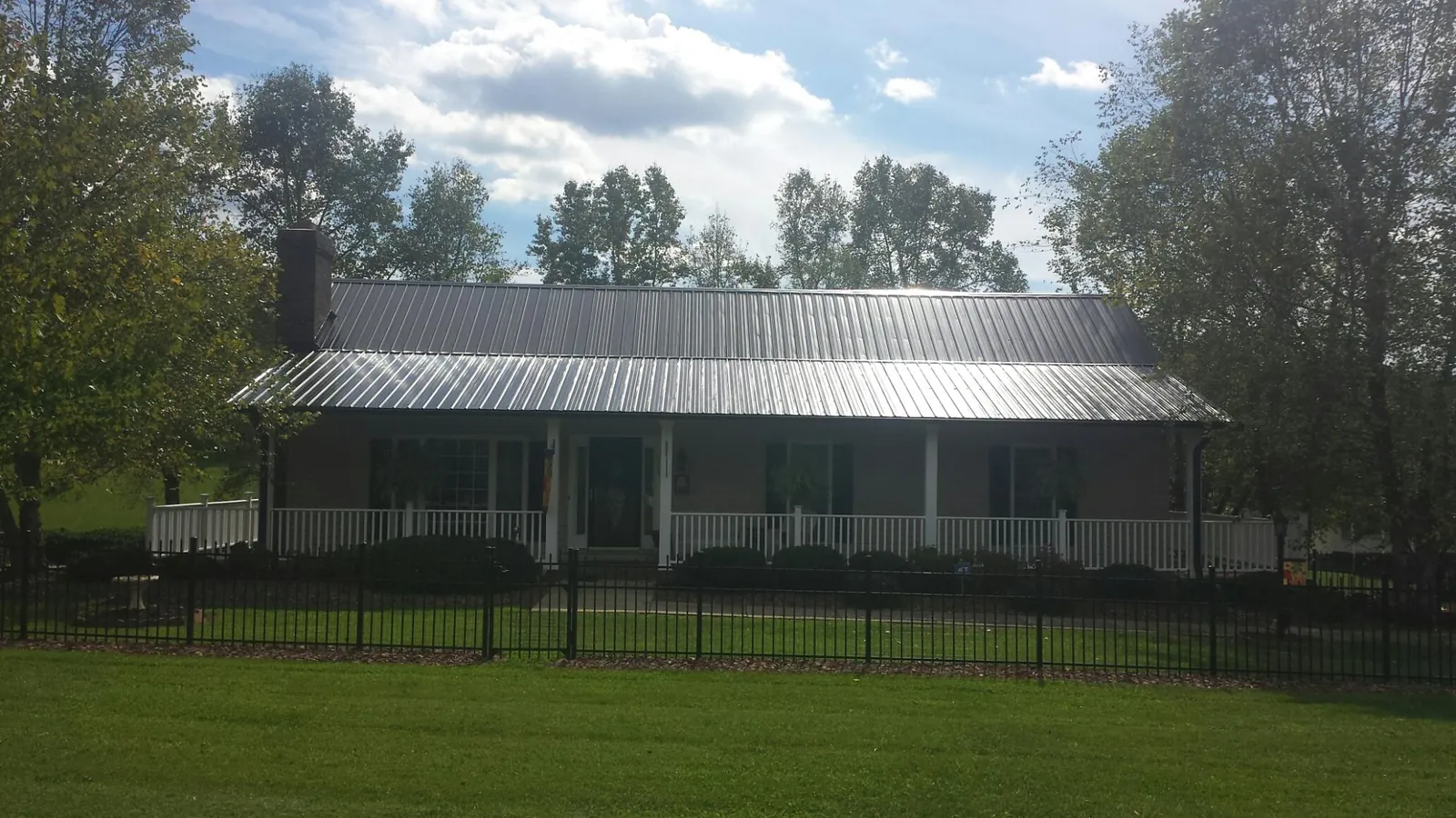 Gray metal roof on a brick ranch with a full width front porch — Gutter Guard Installation work by our crew in Buckingham