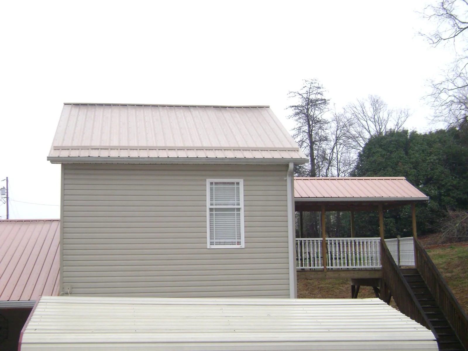 Tan metal roofs on a two story addition and attached porch, from a Roof Replacement job in Buckingham