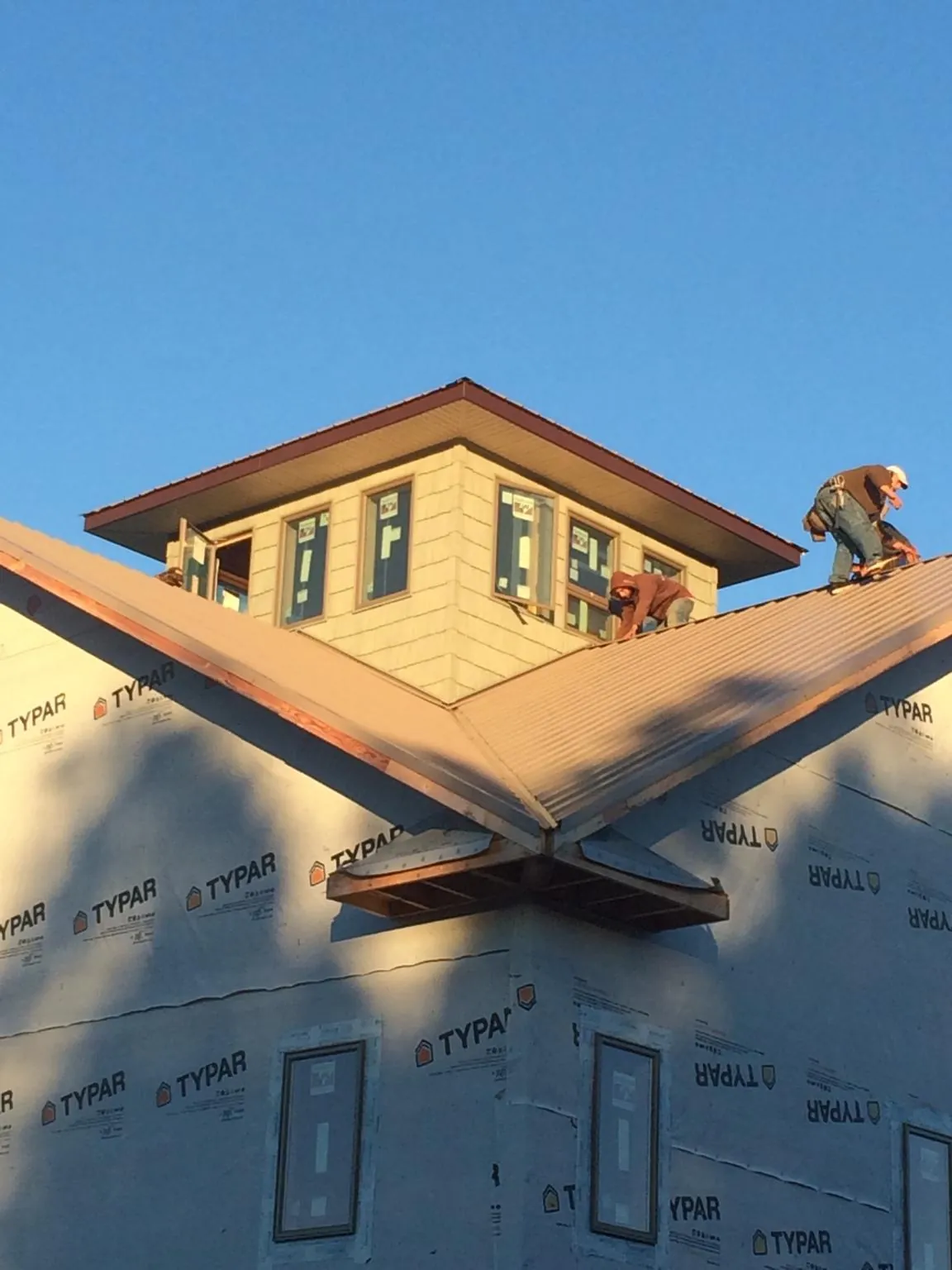 Roofers working around a rooftop cupola on a new metal roof at sunset — Roof Waterproofing in Buckingham by Roofing Brothers